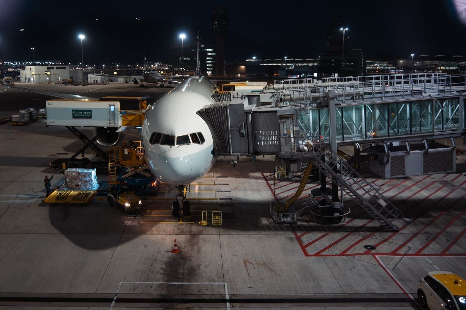 Widebody aircraft being worked by cargo loaders at night