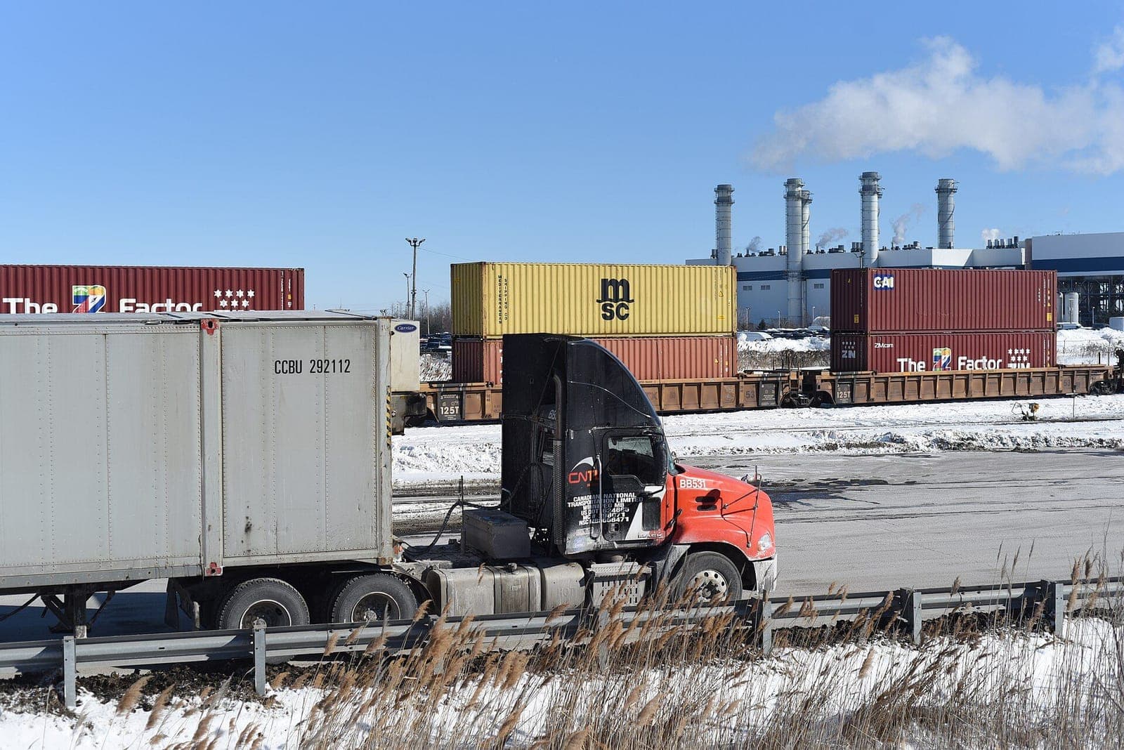 Drayage tractor with a container passing a double-stacked container train