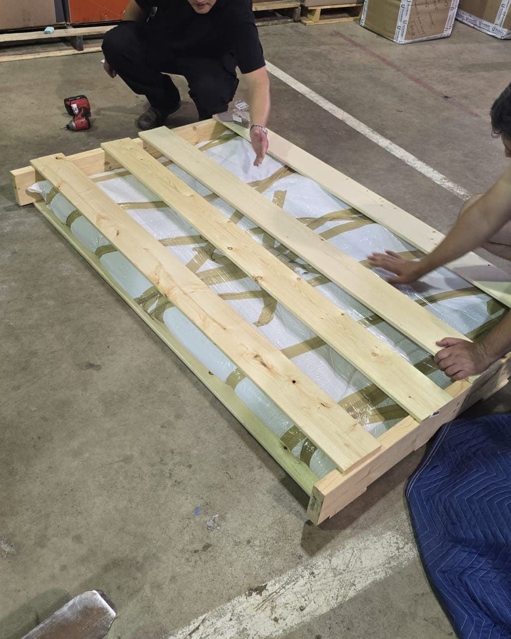 Two crew members closing a custom wooden crate around a wrapped piece