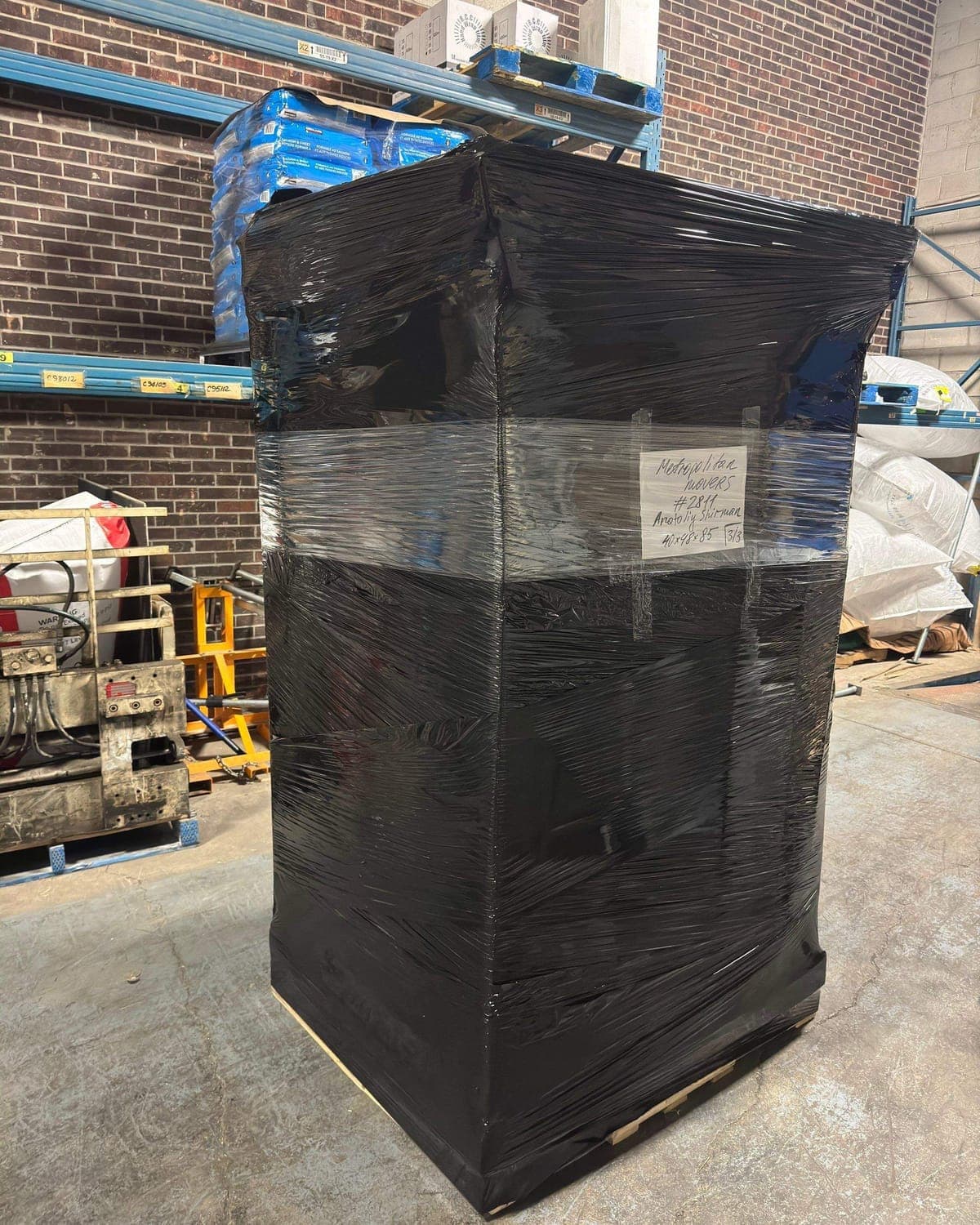 Groupage shipment shrink-wrapped in black film, strapped and hand-labelled