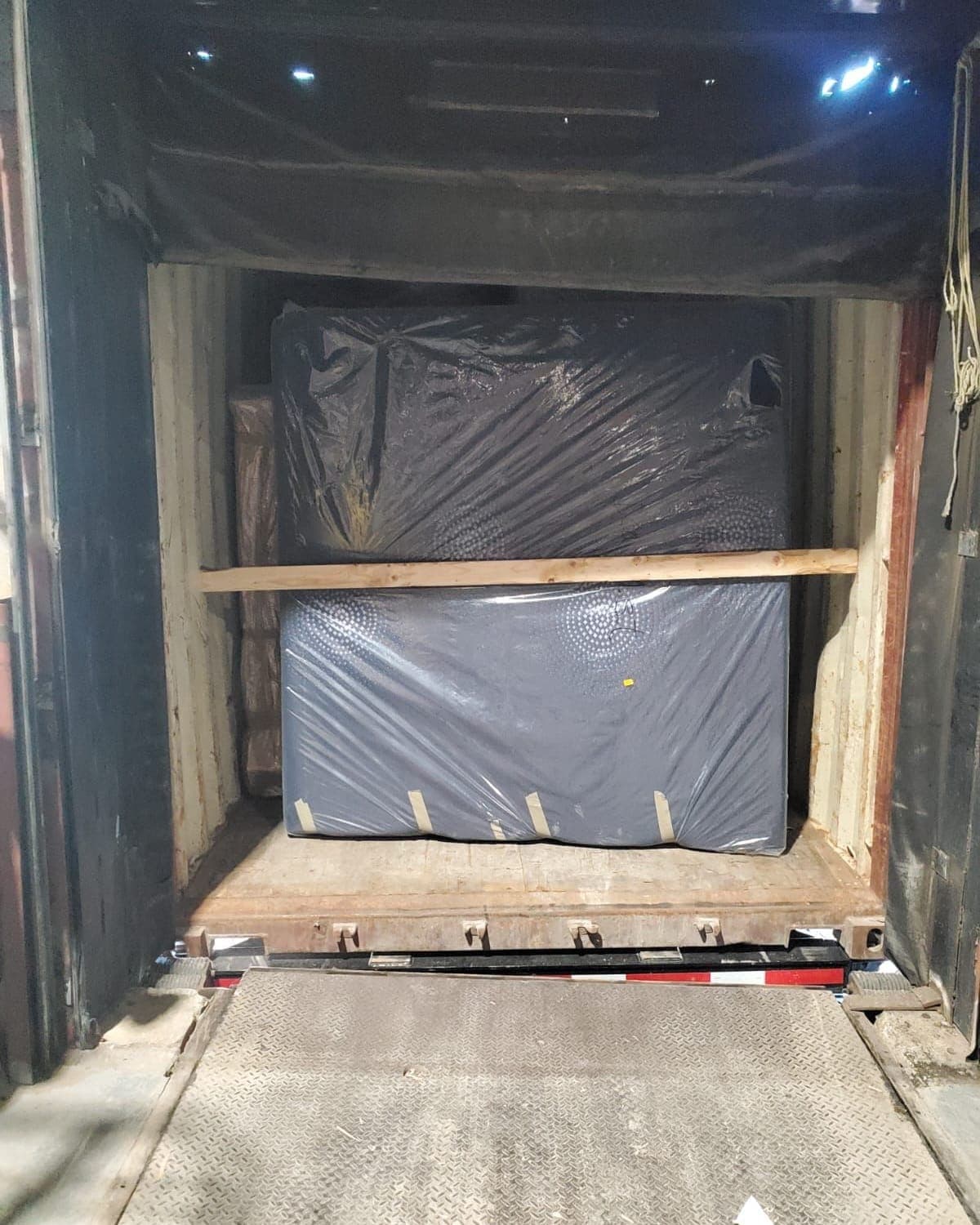 Mattresses in plastic covers braced with lumber inside a shipping container