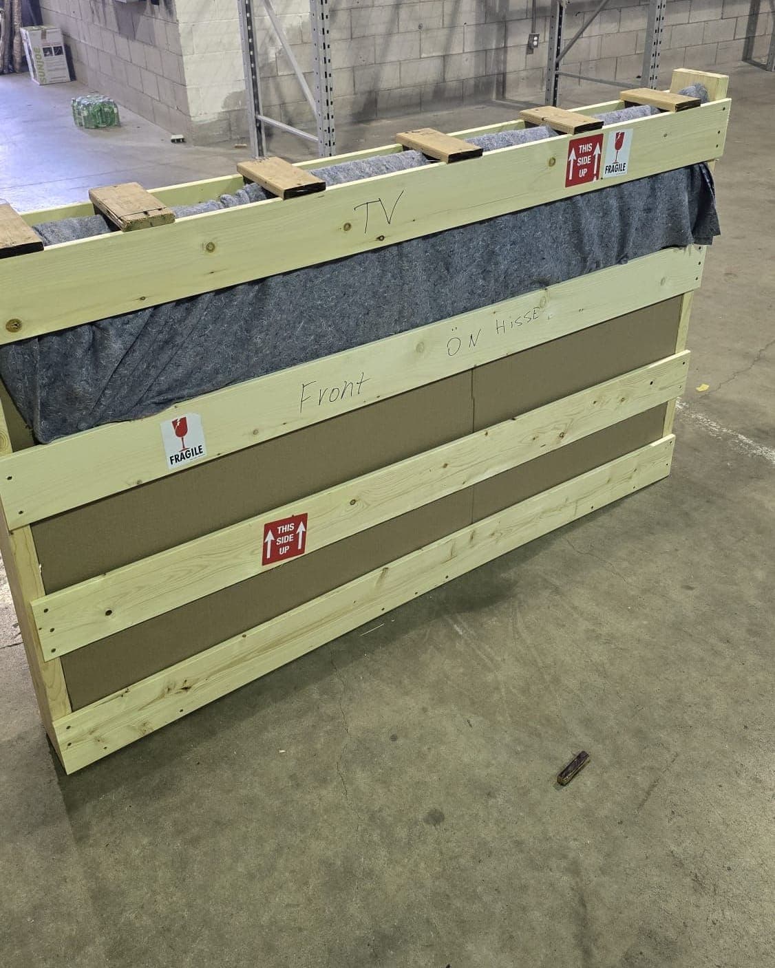 Felt-lined slatted wooden TV crate marked fragile and this-side-up