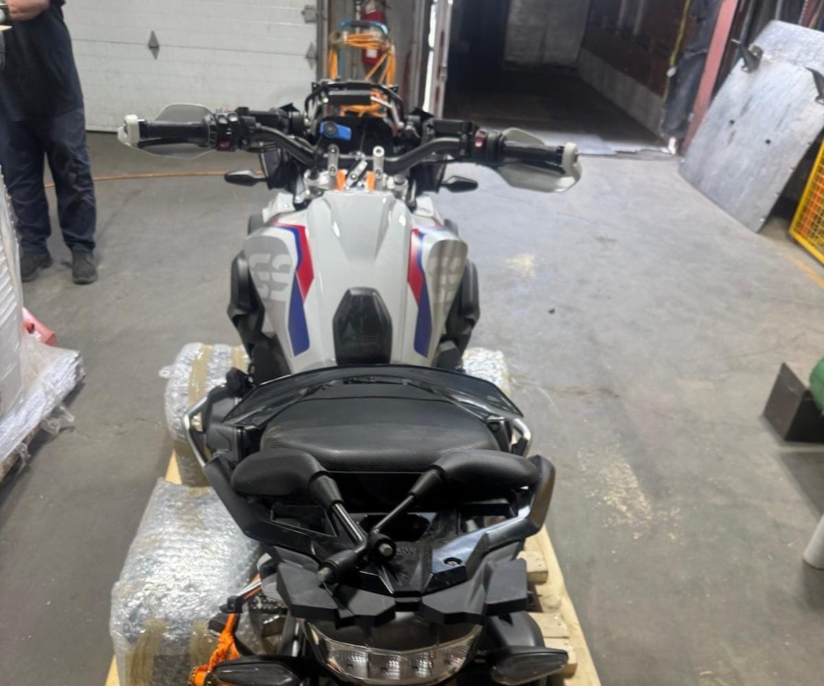 BMW GS adventure bike strapped to a pallet base with bubble-wrap protection along the panniers