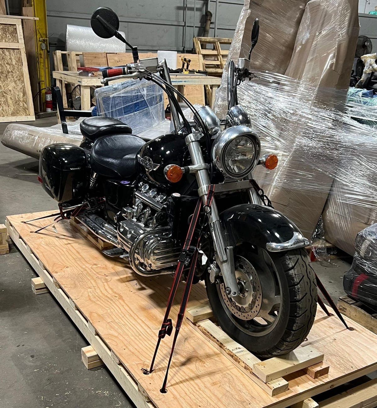 Touring cruiser ratchet-strapped upright to a custom timber base on the warehouse floor