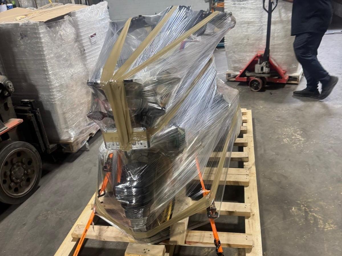 Wrapped motorcycle on its pallet base, moving through the warehouse as a single unit
