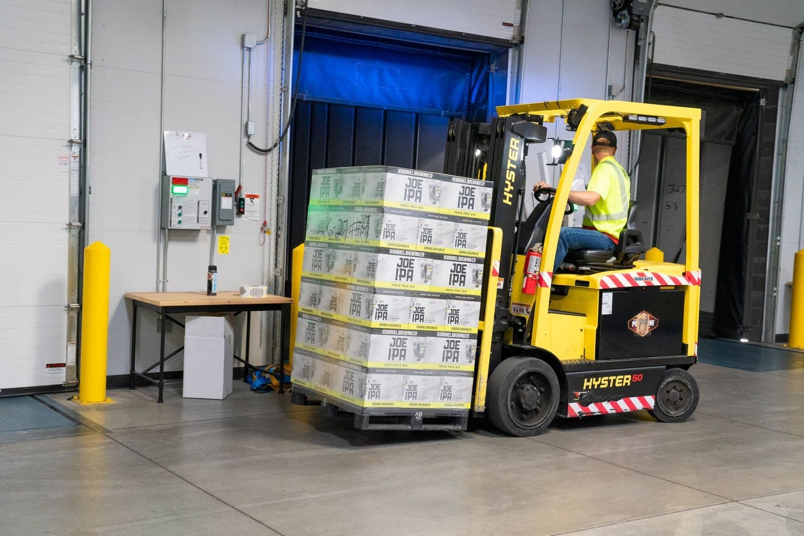 Shrink-wrapped pallet on forklift forks at a warehouse dock door