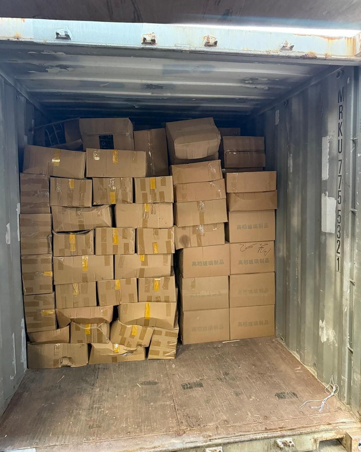 Floor-loaded container stacked to the roof with loose cartons before unloading